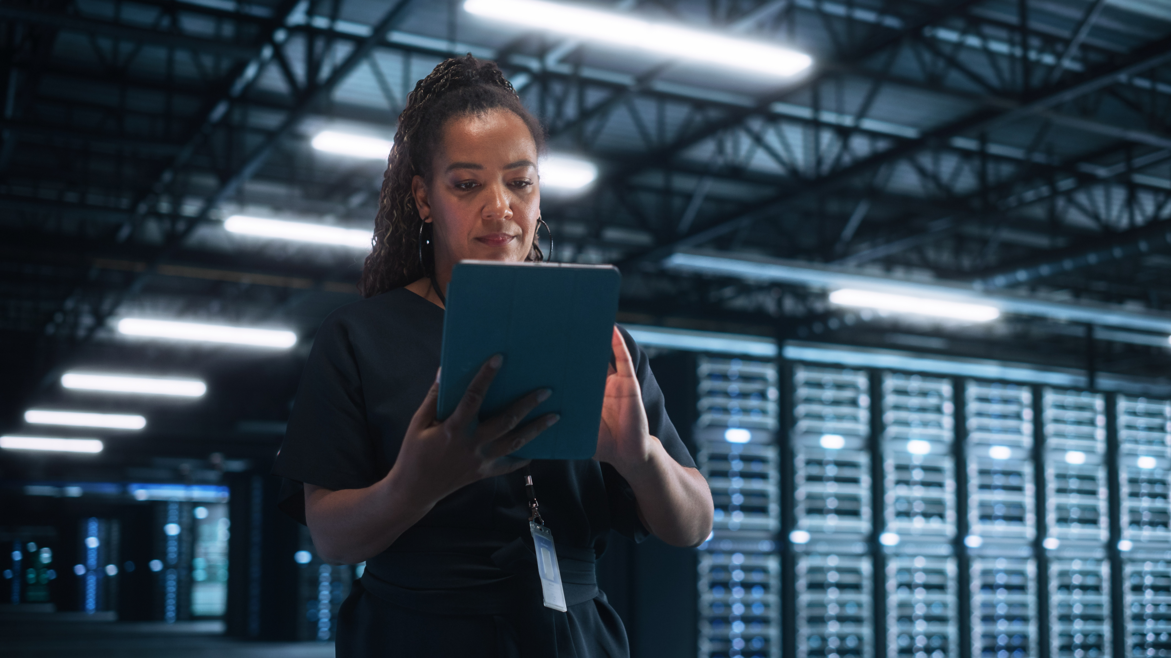 Person using a tablet in a modern industrial warehouse, illustrating operational complexity.